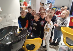 dzieci stoją obok myjki fryzjerskiej