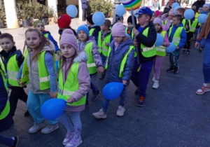 dzieci ubrane na niebiesko i balonami uczestniczą w marszu