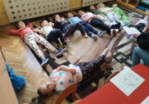 dzieci słuchają opowiadania leżąc