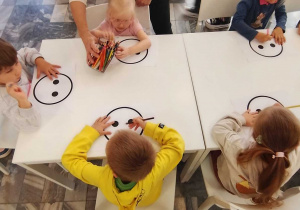 dzieci kończą rysować ilustracje rysując smutną lub wesołą minę