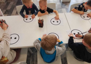dzieci kończą rysować ilustracje rysując smutną lub wesołą minę