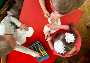 dzieci kolorują serduszka z magicznymi słowami